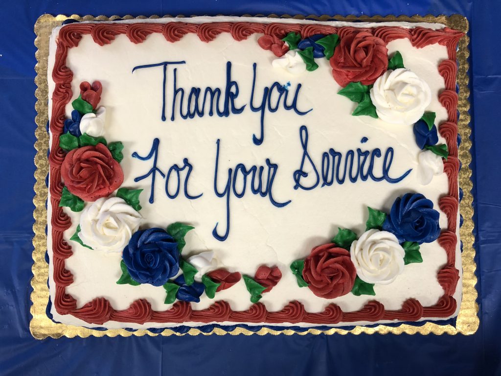 Cake for Veteran's event - says Thank you for your service, decorated with red, white, and blue flowers