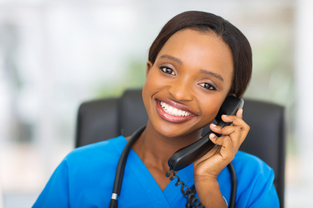 Young black woman in blue scrubs on phone